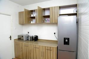 - une cuisine avec des placards en bois et un réfrigérateur dans l'établissement AJ HOMES, à Benin City