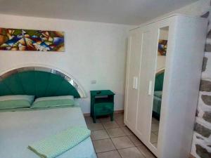 um quarto com uma cama com uma cabeceira verde e um espelho em One bedroom appartement with wifi at Bari Sardo 3 km away from the beach em Bari Sardo