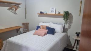 una camera da letto con un letto bianco e cuscini sopra di Vivendas Canaã a Espera Feliz