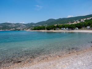 ein Strand mit blauem Wasser und Bäumen im Hintergrund in der Unterkunft Sunset Premium Camping in Klenovica