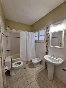 a bathroom with a toilet and a bidet and a sink at La posada del Colibrí in Mendoza