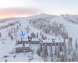 a snow covered hill with trees and a ski resort at VuosselinHelmi 44 in Kuusamo