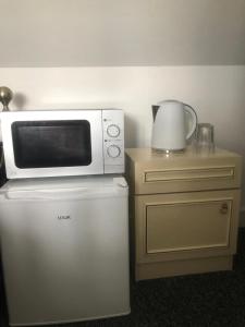 a microwave sitting on top of a refrigerator at Rahal Ilford in Ilford