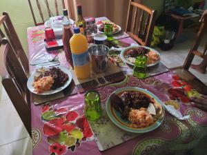 una mesa con platos de comida y botellas de jugo de naranja en Tim's & Mag's Home Stay, en Roseau