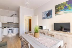 een witte keuken met een tafel en een televisie bij Casa Ristrutturata Parking Condominiale in Diano Marina