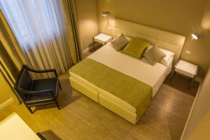 a small bedroom with a bed and a chair at Hotel Universal in Livorno
