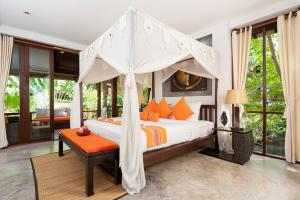 a bedroom with a canopy bed with orange pillows at Ban's Diving Resort SHA Extra Plus in Koh Tao