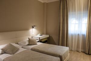 a hotel room with two beds and a window at Hotel Universal in Livorno