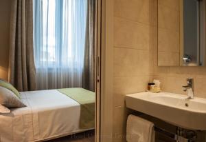 a bathroom with a bed and a sink and a window at Hotel Universal in Livorno