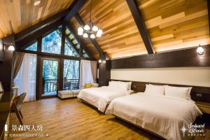 2 camas en una habitación con techos y ventanas de madera en 日月潭森堡萊夫莊園, en Yuchi