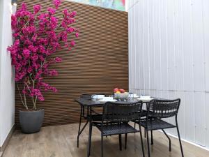 einen Tisch und Stühle mit rosa Blumen und einem Baum in der Unterkunft WEFLATING Fira in Hospitalet de Llobregat