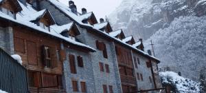 a building covered in snow with a mountain in the background at Duplex Calle El Tillo in Escarrilla