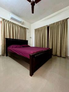 a bedroom with a bed with purple sheets and curtains at Coast & Comfort Stays - 2 BHK home in Panjim in Panaji