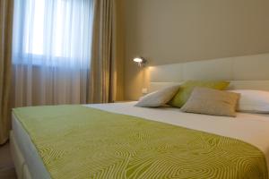 a bedroom with a large bed with a green comforter at Hotel Universal in Livorno