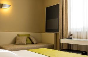a bedroom with a bed and a couch and a tv at Hotel Universal in Livorno