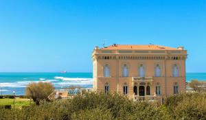 a large building with the ocean in the background at Hotel Universal in Livorno