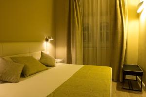 a bedroom with a bed with a yellow blanket and a window at Hotel Universal in Livorno