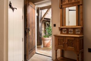 une porte ouverte menant à un couloir avec une armoire en bois et un miroir dans l'établissement The Stables - The Inn Collection Group, à Whitby