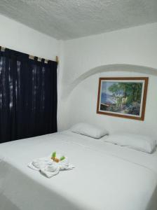 Una cama blanca con una toalla encima. en Íkaro Suites Cancún, en Cancún