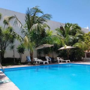 una gran piscina azul con sillas y sombrillas en Íkaro Suites Cancún, en Cancún