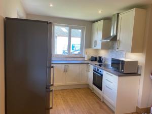 a kitchen with white cabinets and a black refrigerator at Immaculate 2 Bed property in rural location in Alloa