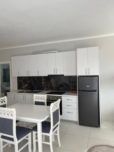 een keuken met een tafel en een zwarte koelkast bij Fishta hotels in Velipojë