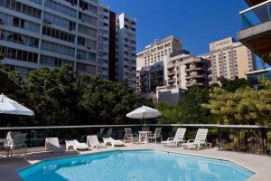 una piscina con sillas, mesas y sombrillas en una ciudad en IPF2084 - Ipanema Tower Residence Service - Ipanema, en Río de Janeiro