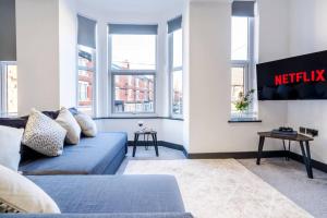 a living room with a blue couch and windows at Wiverton Apt #4 - Central Location - Free Parking, Fast WiFi and Smart TV by Yoko Property in Nottingham