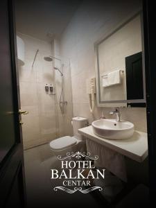 a bathroom with a toilet and a sink and a mirror at Hotel Balkan Centar in Bijeljina