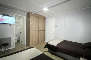 1 dormitorio con 1 cama y TV de pantalla plana en Juku Hostal, en Calama