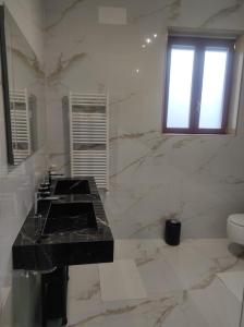 uma casa de banho em mármore com um lavatório e um WC. em Palazzo in Corte - Nel cuore di Bari em Bari