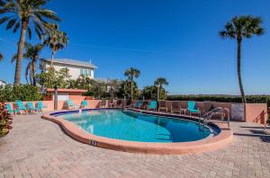 een groot zwembad met stoelen en palmbomen bij Coquina Moorings 203 in Bradenton Beach