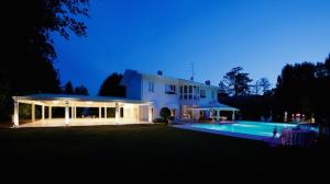 una gran casa blanca con piscina por la noche en Villa Patrizia B&B, en Magnago