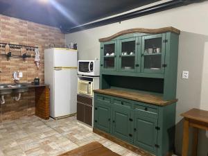 cocina con armarios verdes y nevera blanca en Pousada Casa da Maga - Centro en Blumenau