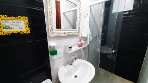bagno con lavandino bianco e specchio di Pousada Casa da Maga - Centro a Blumenau