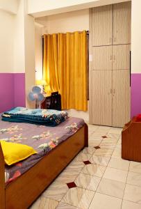 a bedroom with a bed and a yellow curtain at Raga Homestay - Urban Comfort- 2BHK Apartment in Guwahati