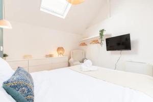 a white bedroom with a white bed and a tv at Lille Citadelle Charming house with courtyard in Lille
