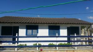 a white house with blue shutters and a blue fence at Elvi Apartment 2 in Rachonio