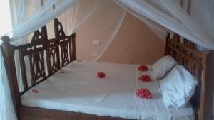 ein Bett mit roten Blumen darüber in der Unterkunft MINAZI BEACH BUNGALOWS in Nungwi