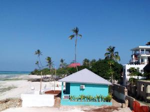 MINAZI BEACH BUNGALOWS في نونغوي: مبنى أزرق على شاطئ به أشجار نخيل