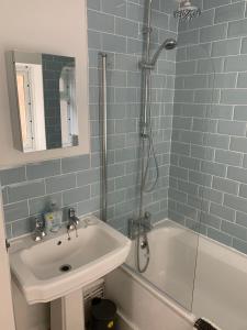 a blue tiled bathroom with a sink and a shower at Ryde Beach Garden Apartment in Ryde