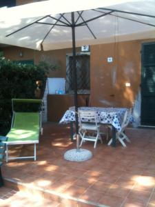 uma mesa e cadeiras sob um guarda-sol num pátio em Residence Giannella - Pitosforo 46 em Giannella