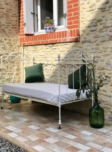 una cama de metal en un patio bajo una ventana en Plages du débarquement et bord de mer pour 4 personnes, en Grandcamp-Maisy