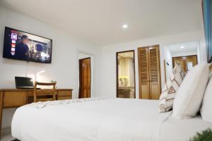 a bedroom with a white bed with a tv on the wall at Hotel Guane in Bucaramanga