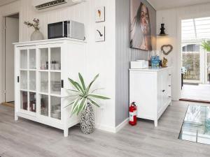 una sala de estar con un armario blanco y una planta en Holiday home Juelsminde LII, en Sønderby