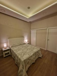 1 dormitorio con 1 cama y 2 lámparas en 2 mesas en Aquí es, en Badajoz