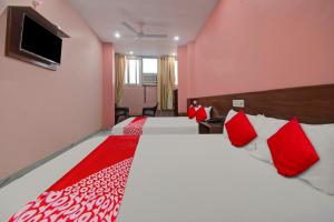 a bedroom with two beds with red and white pillows at Hotel Rameshwaram in Jaipur