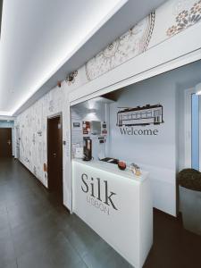 a lobby with a white counter with a sign on the wall at Silk Lisbon in Lisbon