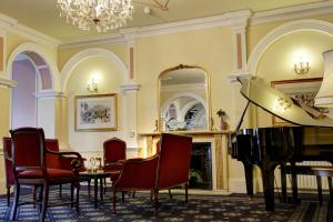 a living room with a piano and a table and chairs at Royal Victoria Hotel in Hastings