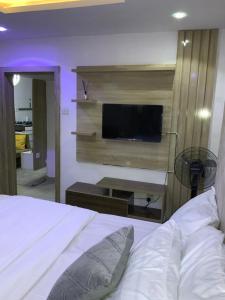 - une chambre avec un lit et une télévision murale dans l'établissement GREEK VIEW APARTMENT VICTORIA ISLAND, à Lagos